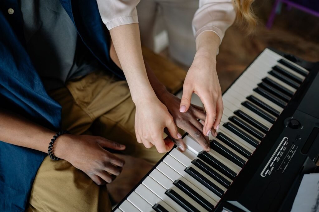 A detailed view of hands playing and teaching piano keys in an indoor setting.